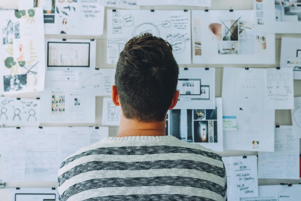 Man looks at wall with post its and information.