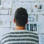 Man looks at wall with post its and information.