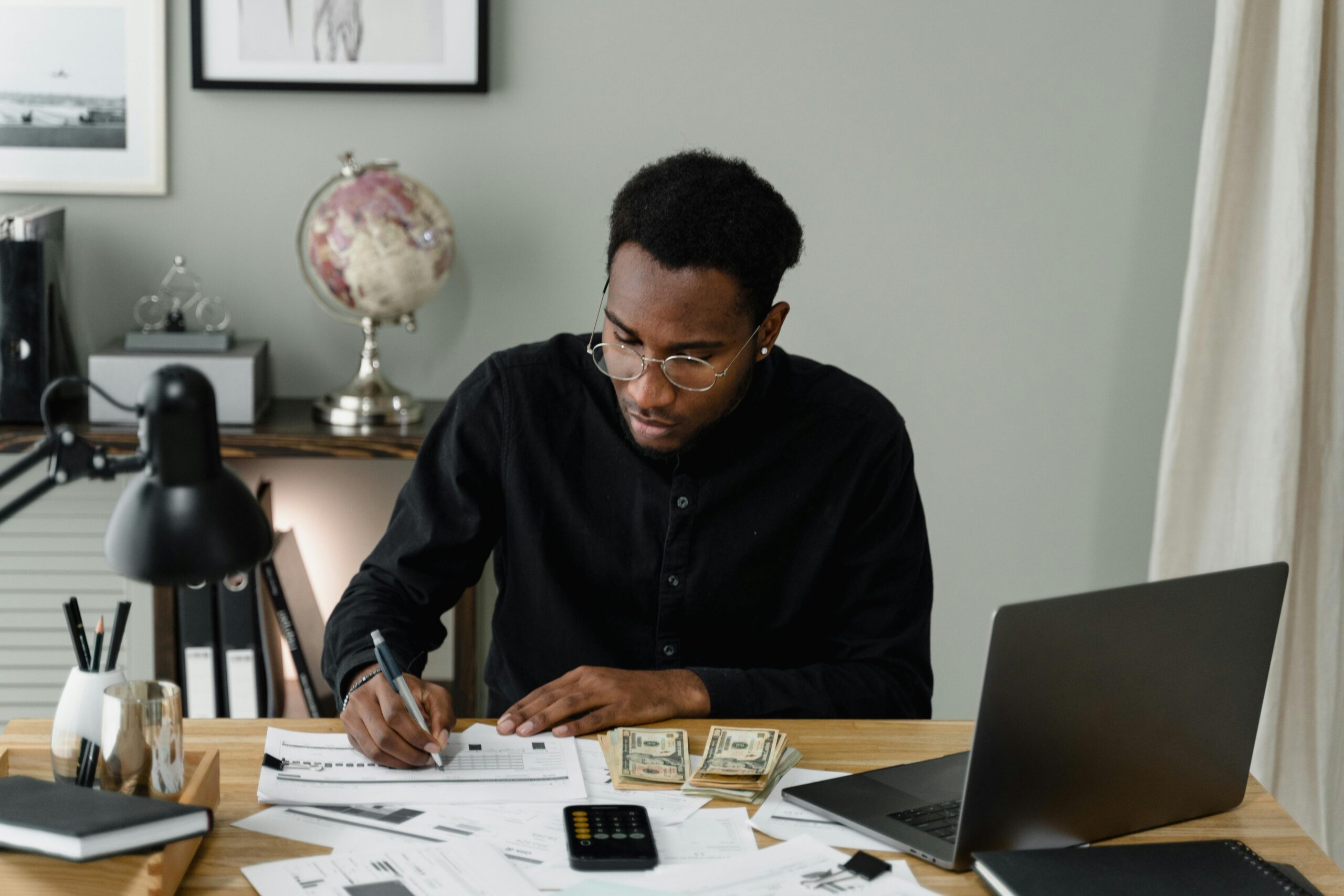 man sits at desk with computer in front of him doing some paper work.