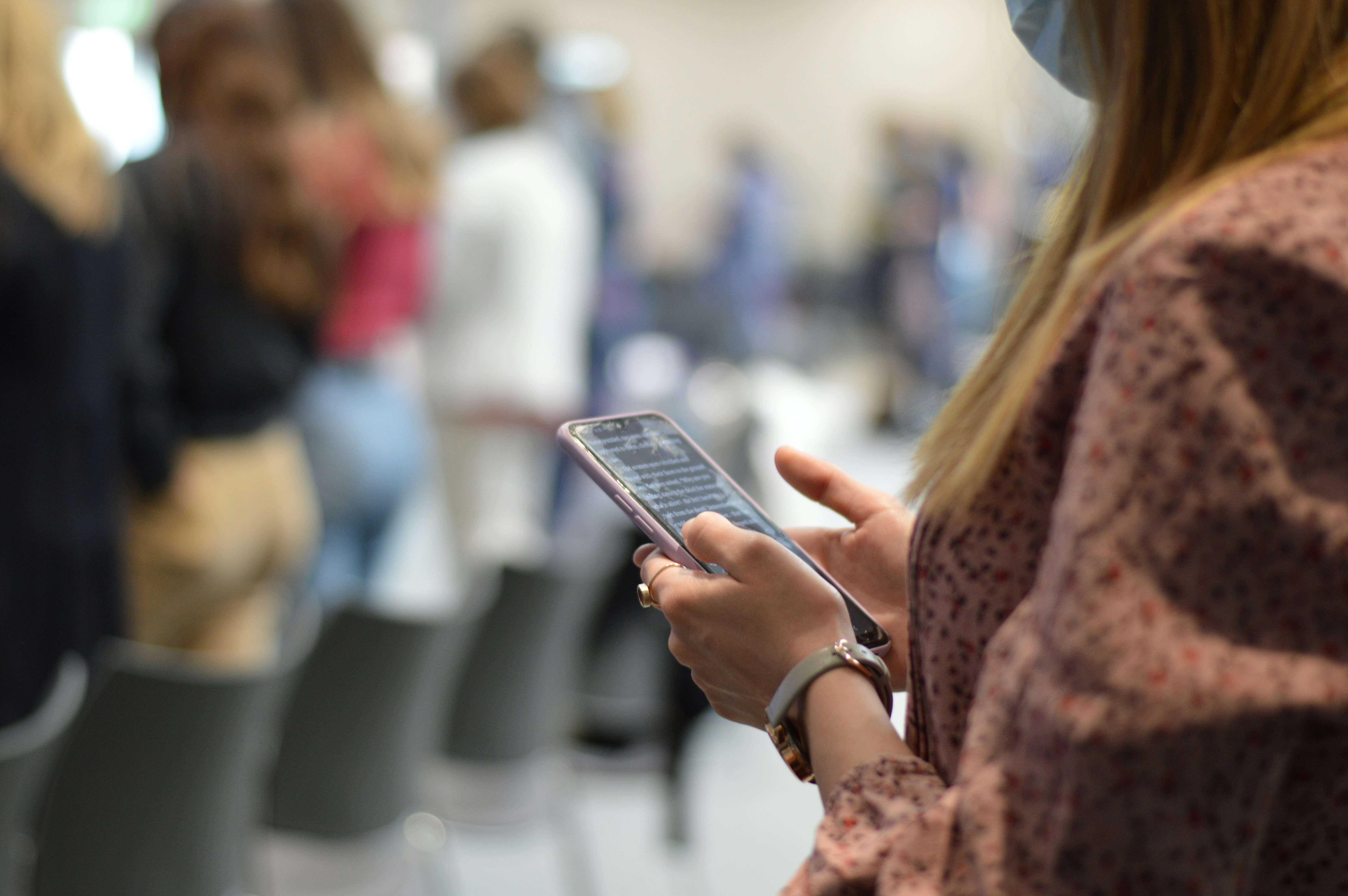 a person holding a phone standing in line. You don't see anyone's faces